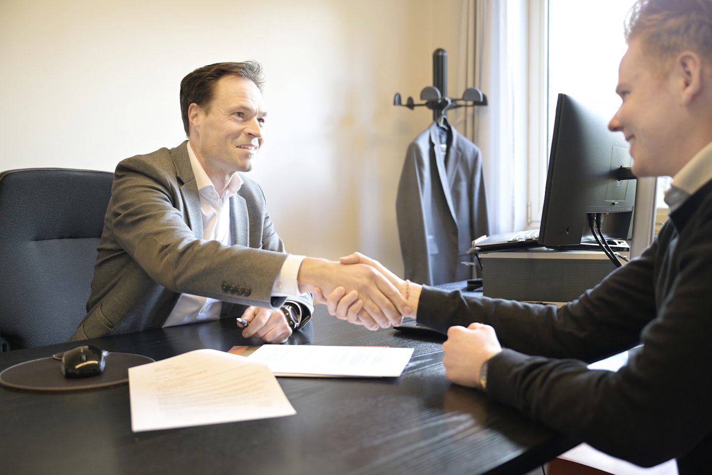 Two professionals shaking hands over a business agreement